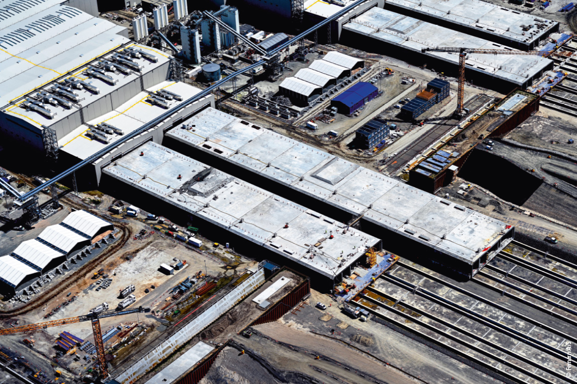 在丹麦洛兰岛的罗德比港，五条生产线正同步浇筑 79 个巨型标准隧道管节。每个管节长约 220 米、宽 43 米，重量超过 7.3 万吨