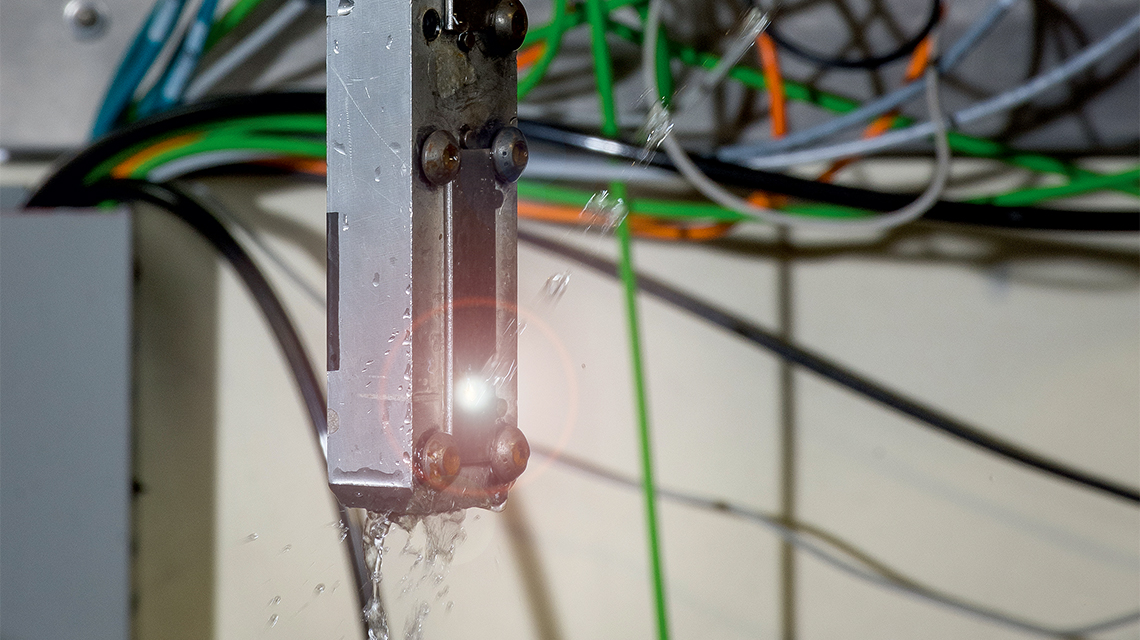 使用激光喷丸方式强化金属件的过程为：将高功率激光光束射向工件，同时喷水，让水流流过工件。 