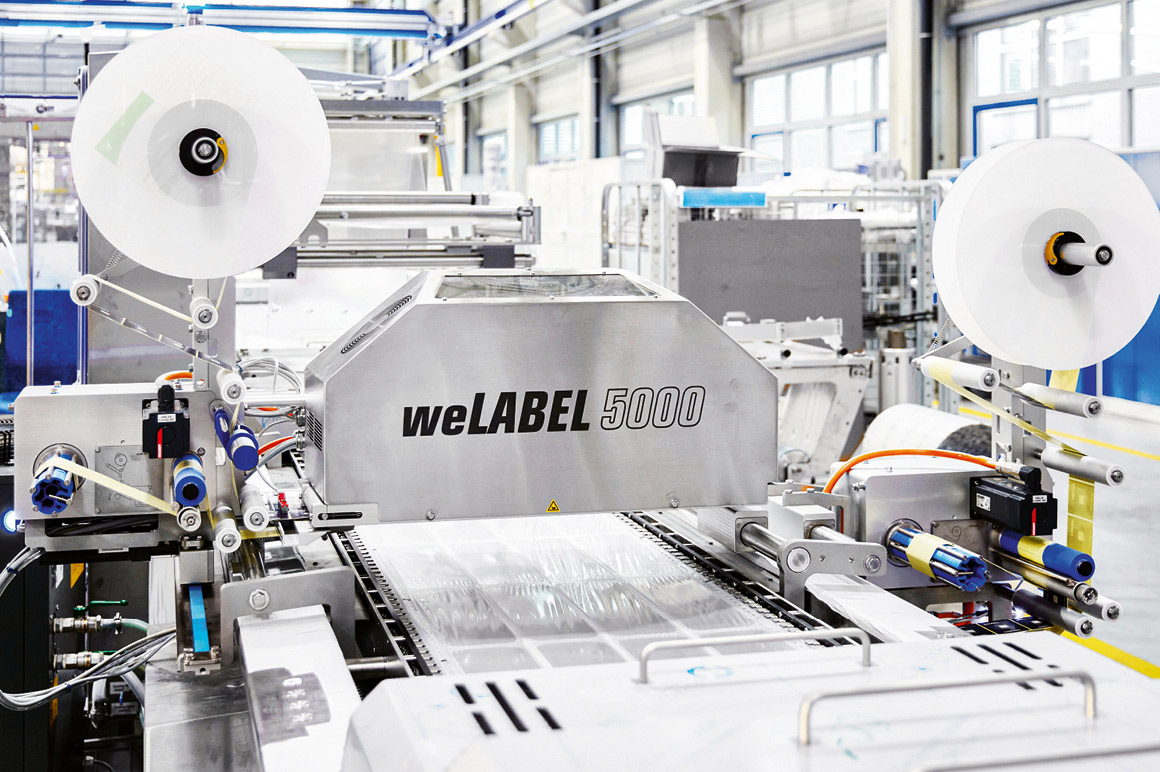 根据需求，包装机可灵活配备最多四台 weLABEL 贴标机（图示为一套顶膜承载工位与一套底膜承载工位）